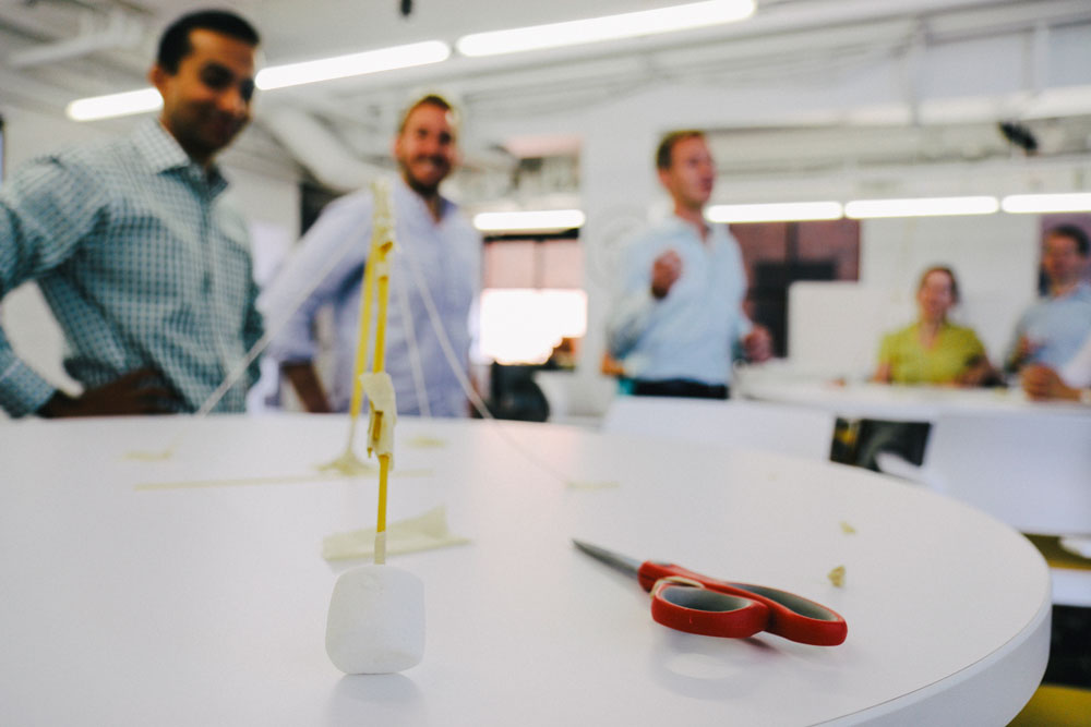 A team stands around their marshmallow challenge failure.