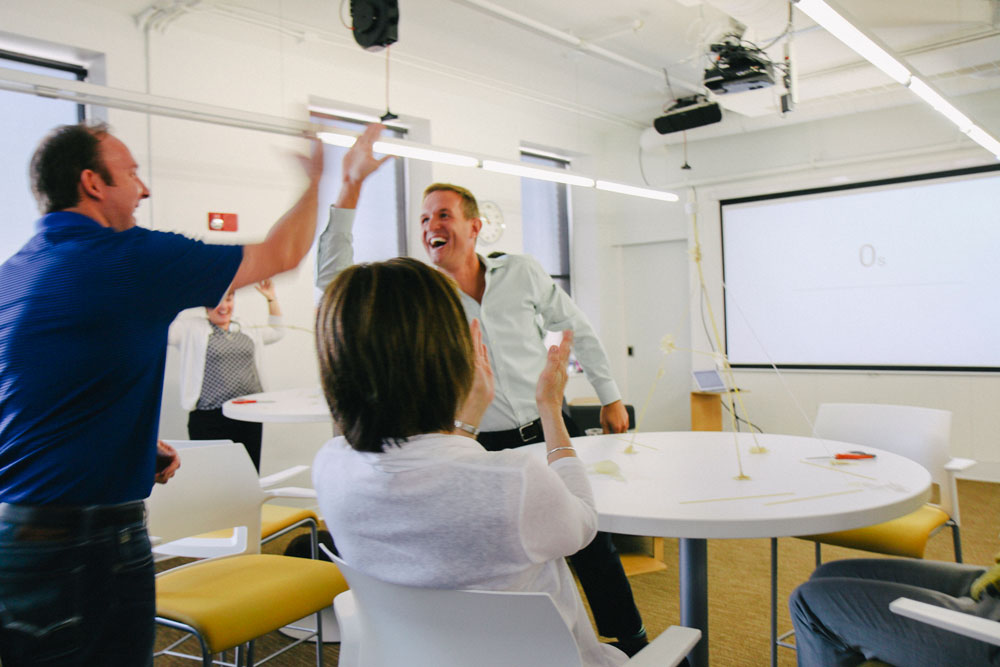 Group members high-five after a successful ideation exercise.