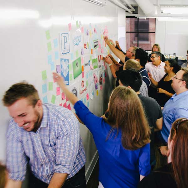 Workshop participants rush to the whiteboard for an ideation exercise.