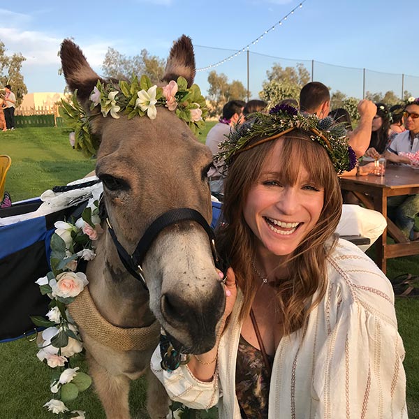 I smile at the camera next to a donkey in a matching flower crown.