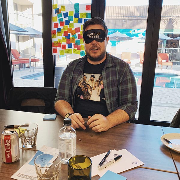 A designer sits blindfolded assembling a pen.