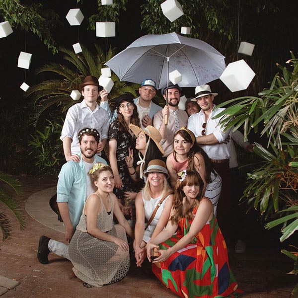 The team poses for a photo with suspended foam cubes and an umbrella.