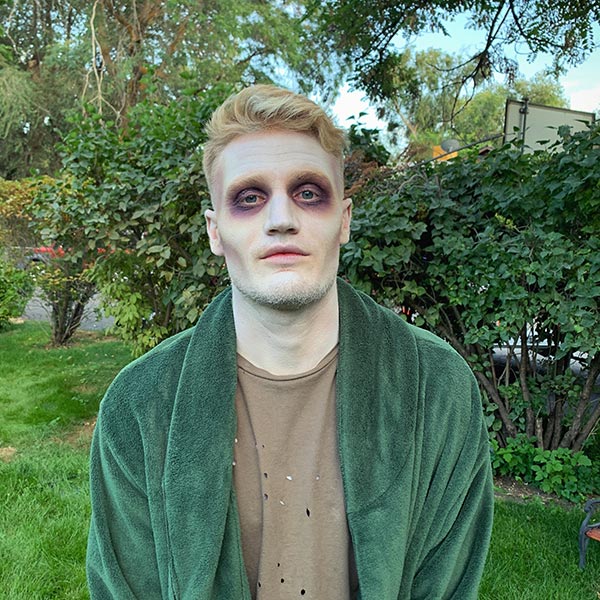 A man stands in zombie makeup on set.