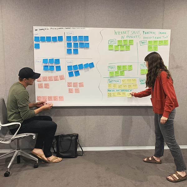 Two people at a white board ideate on a new campaign.
