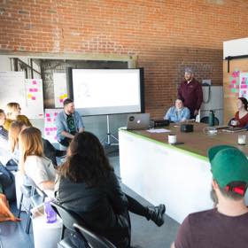 Workshop participants rush to the whiteboard for an ideation exercise.