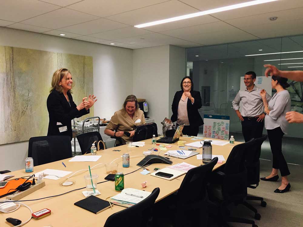 A group of IBM and Lee Hecht Harrison employees laugh as they take a break from the ideation session.