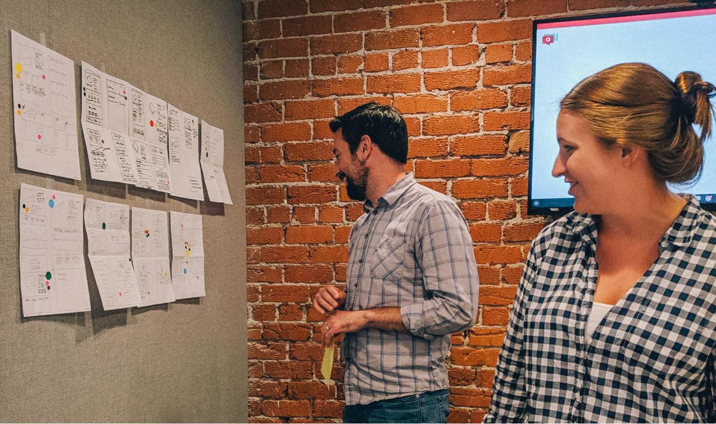 A designer and copywriter laugh at some of their brainstorming sketches